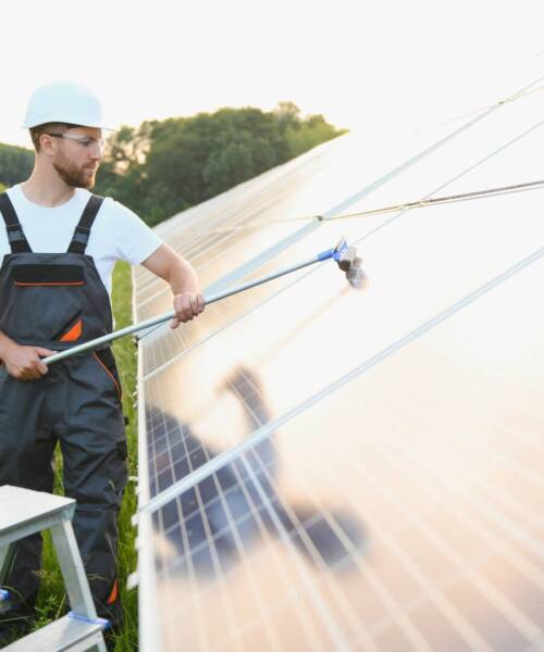 A handyman cleaning solar panels form dust and dirt.